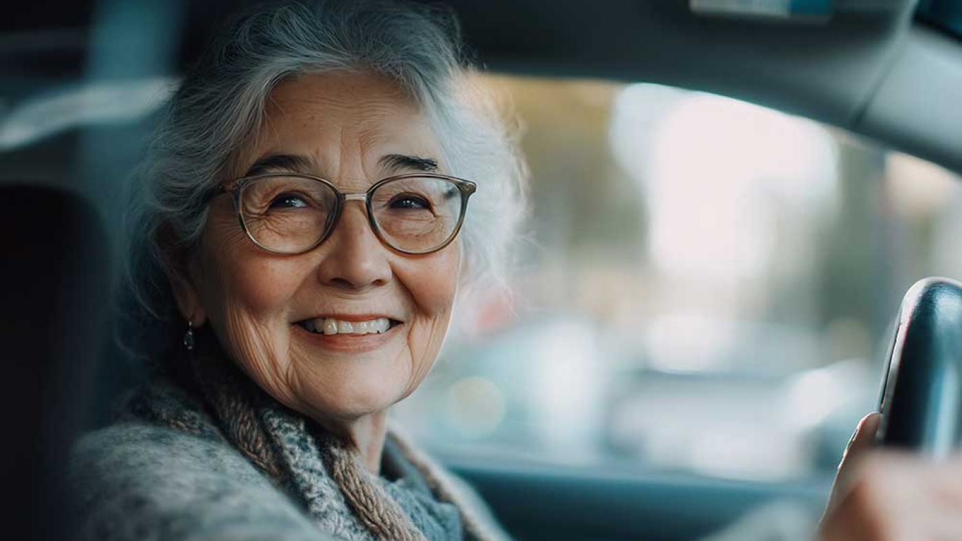 An elderly lady wearing glasses driving a car