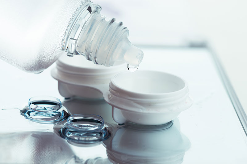adding solution to a contact lens case to care for them